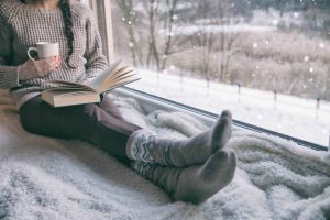 Woman reading a book in front of a window.