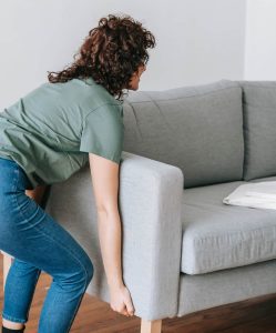 A woman lifting a couch.