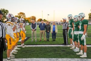 High school football players standing alongside referees and supporters.