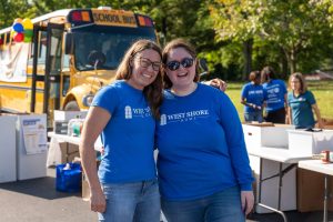 Two West Shore Home employees standing in front of a school bus as part of United Way's Stuff the Bus Campaign.