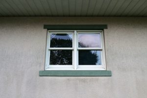 An old exterior window in a green frame.