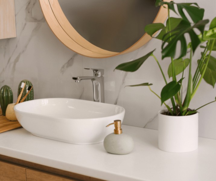 A white bathroom vanity with a plant.