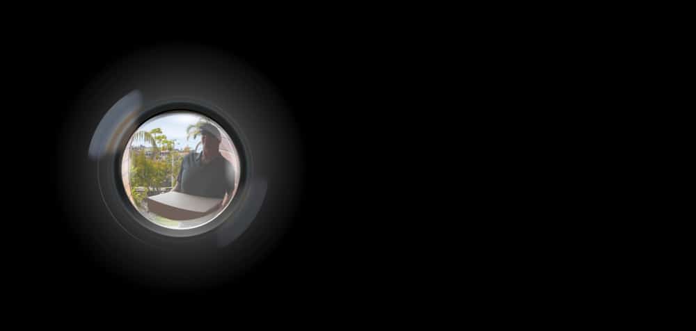 Image of a delivery man through a peep hole on a door.