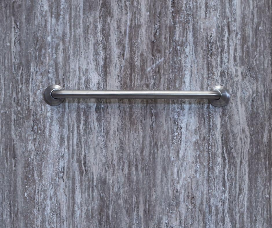 A silver horizontal grab bar on a stripe design acrylic shower wall.