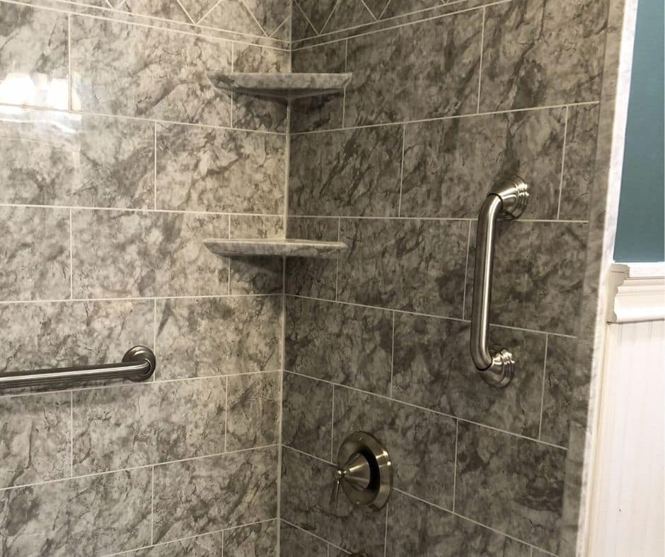 A vertical grab bar in a acrylic laser etched tile shower.