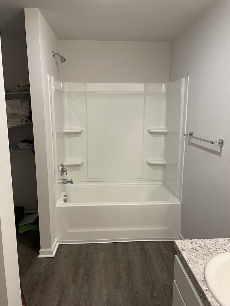 A white tub shower combo with built-in shelves.