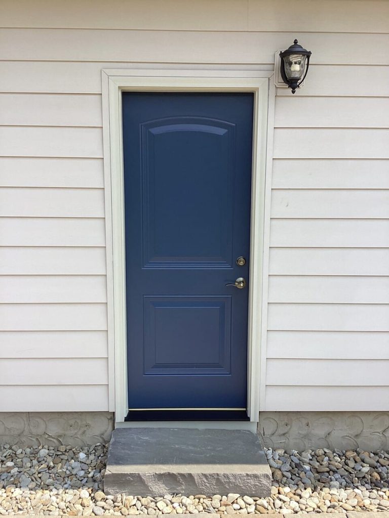 A new enzian blue single entry door on a neutral home.