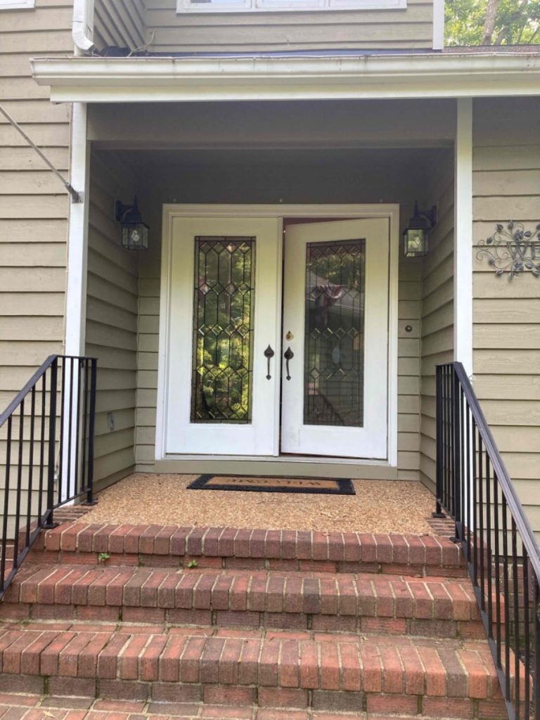 An old white door on a neutral home and brick staircase.