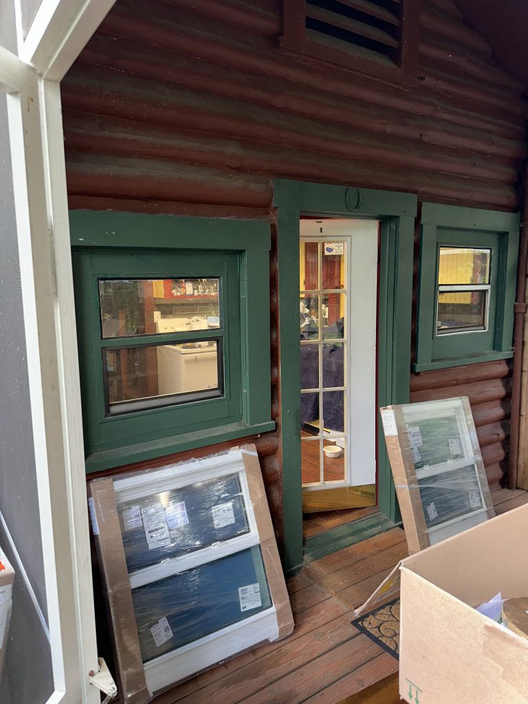 Old green windows on the porch of a log cabin home.