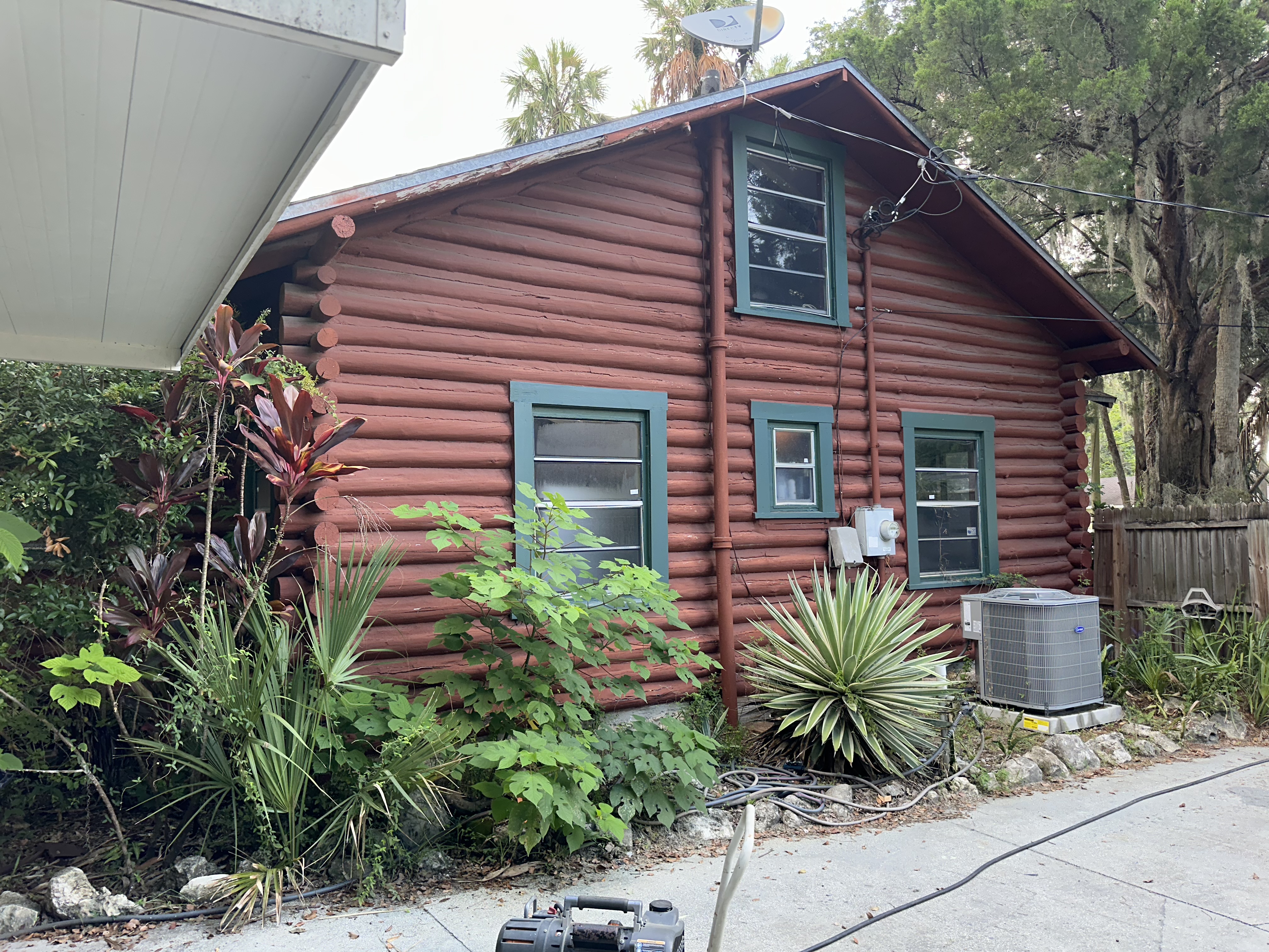 Old green windows on the side of a wood Florida home.