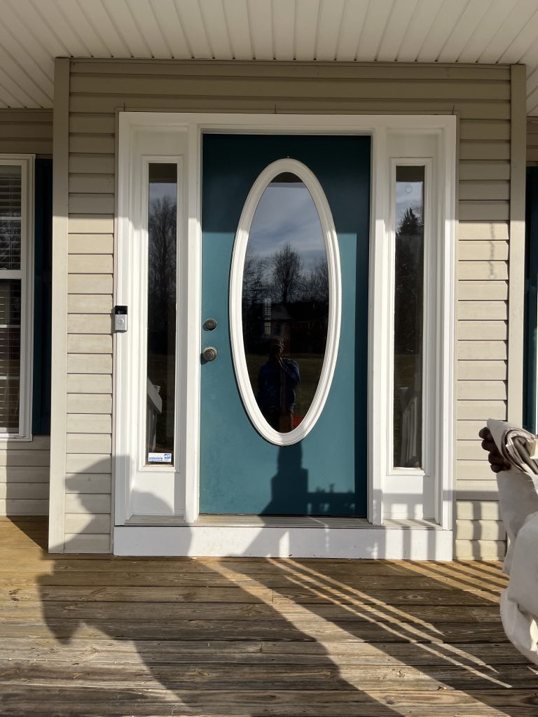 Outdated blue door with white trim on a neutral house.